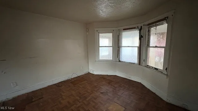 Spare room with a textured ceiling and baseboards