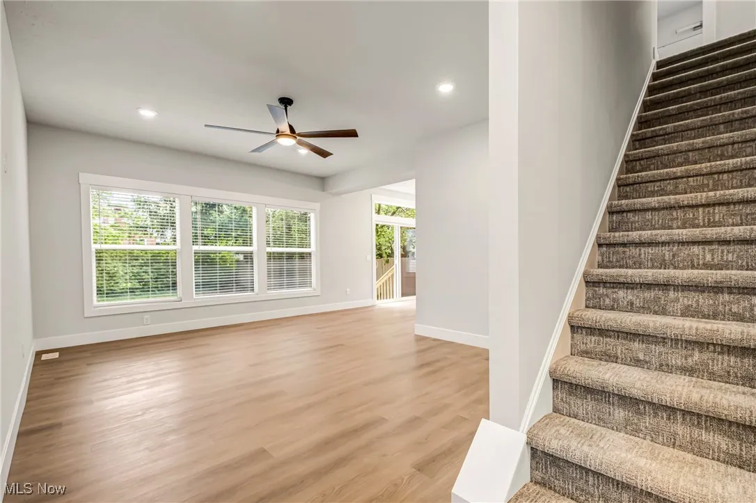 Stairway featuring plenty of natural light, ceiling fan, and light wood-type flooring