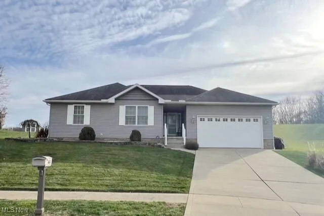 Ranch-style house featuring a front yard, an attached garage, and driveway
