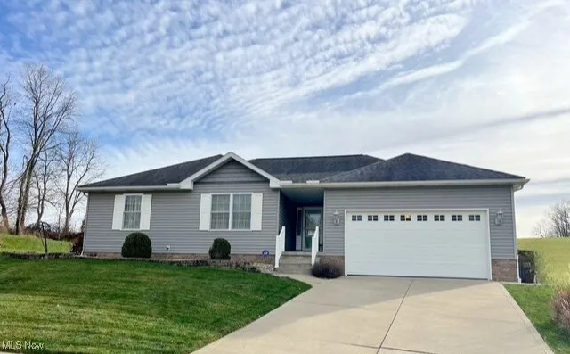 Ranch-style house with an attached garage, driveway, and a front yard