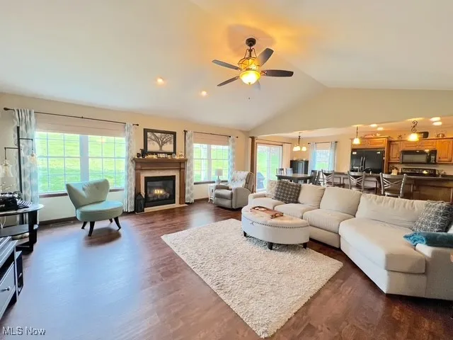 Living room featuring lofted ceiling, dark wood-style floors, ceiling fan, a fireplace with flush hearth, and recessed lighting