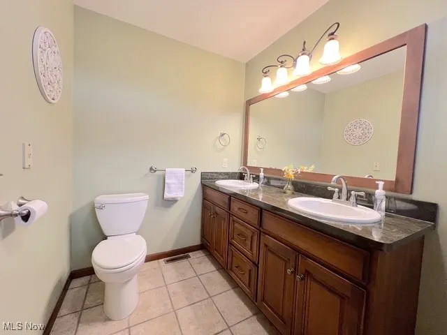 Bathroom with double vanity and light tile patterned floors