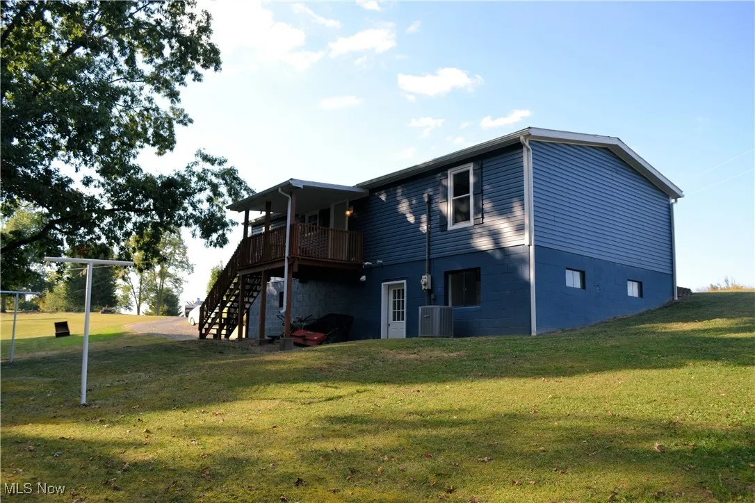 Rear view of property with stairs, a lawn, and a wooden deck