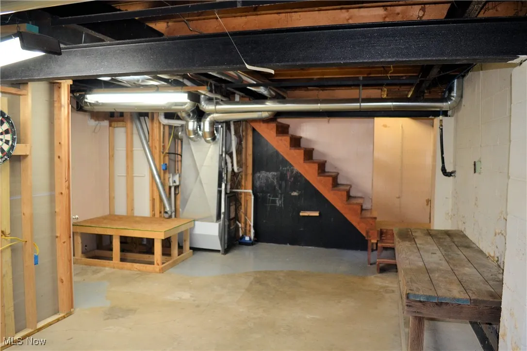 Unfinished below grade area featuring stairway and heating unit