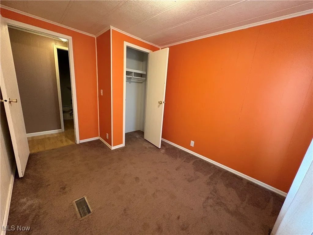 Unfurnished bedroom featuring carpet, a closet, and ornamental molding