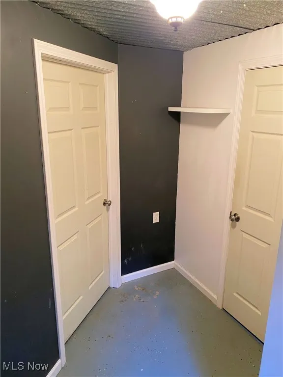 Unfurnished bedroom featuring finished concrete flooring and baseboards
