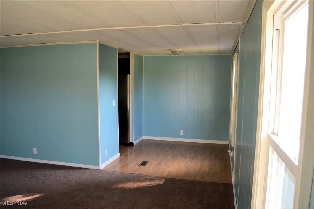 Empty room featuring dark wood-type flooring and wood walls