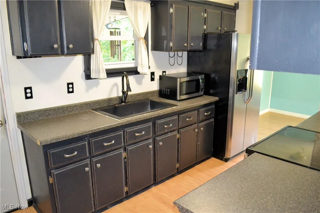 Kitchen featuring dark countertops, light wood-style flooring, and appliances with stainless steel finishes