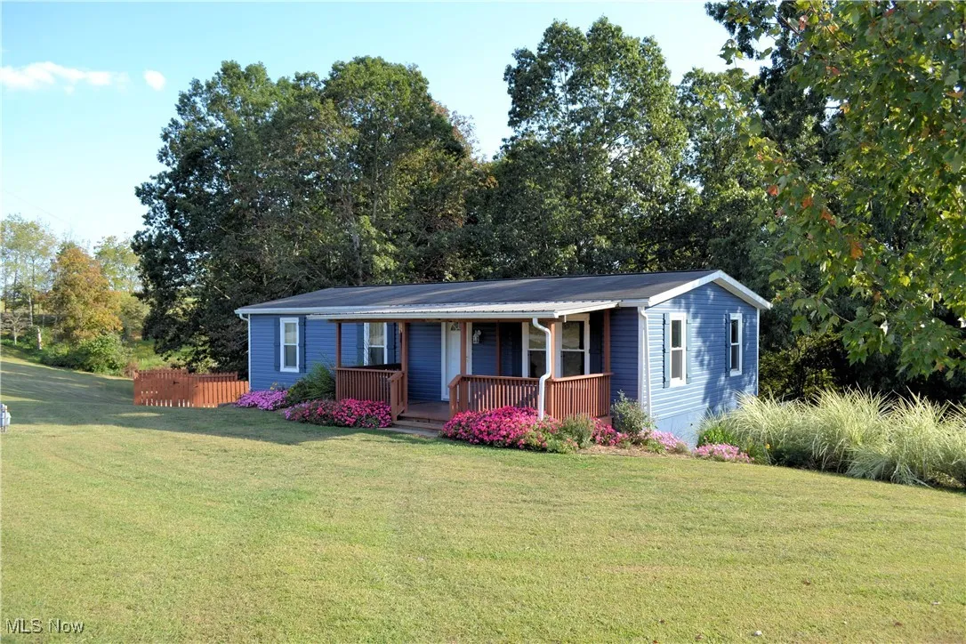 View of front of home featuring a front yard, a porch, and view of scattered trees