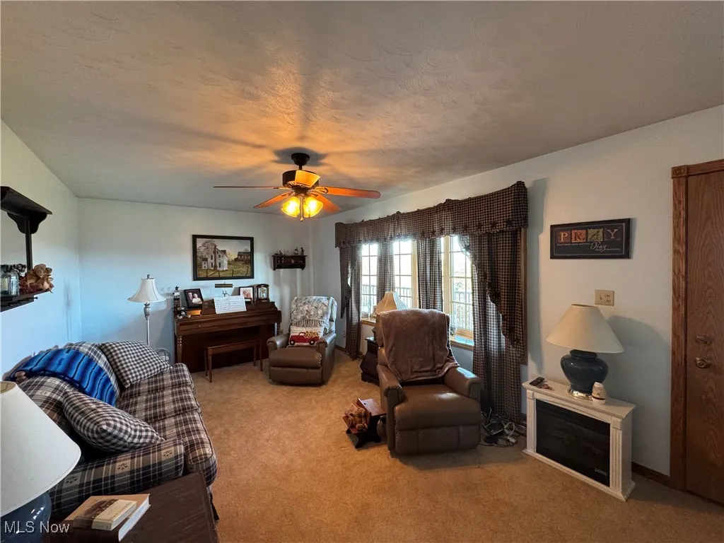 Living room with light carpet, ceiling fan, and a textured ceiling