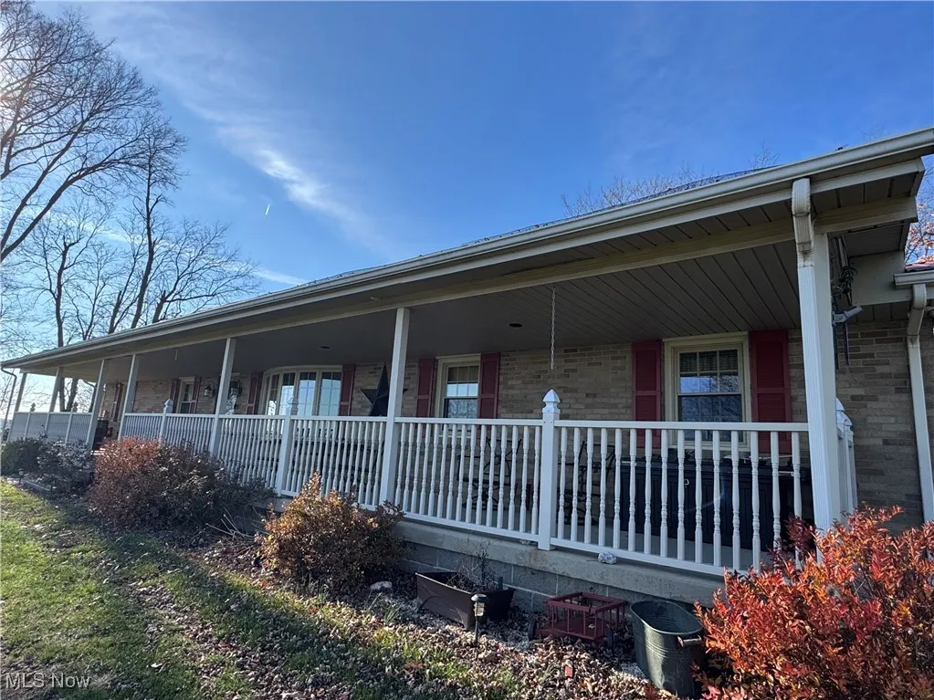 View of side of home with a large porch and brick siding