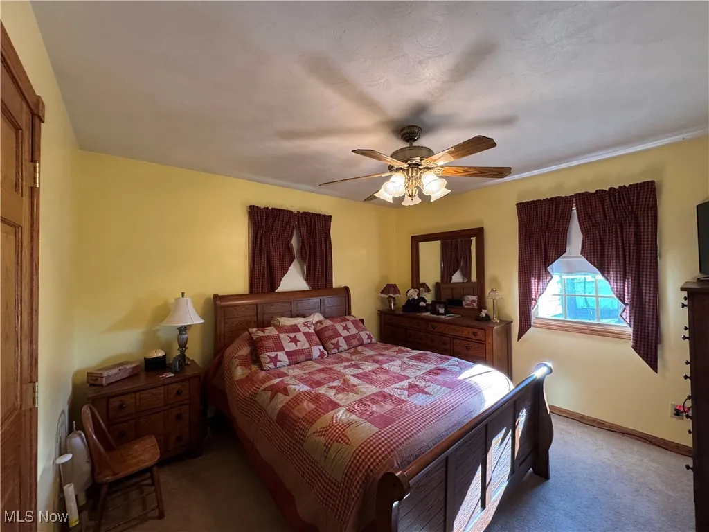 Carpeted bedroom with a ceiling fan and baseboards