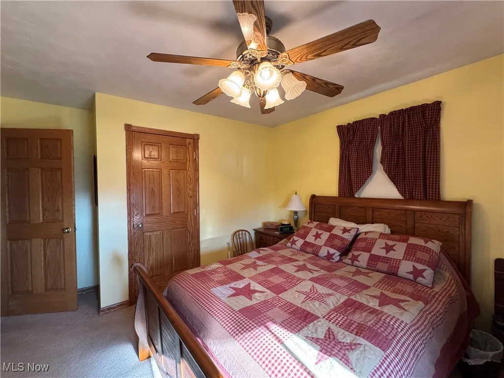 Bedroom with a closet, ceiling fan, and carpet