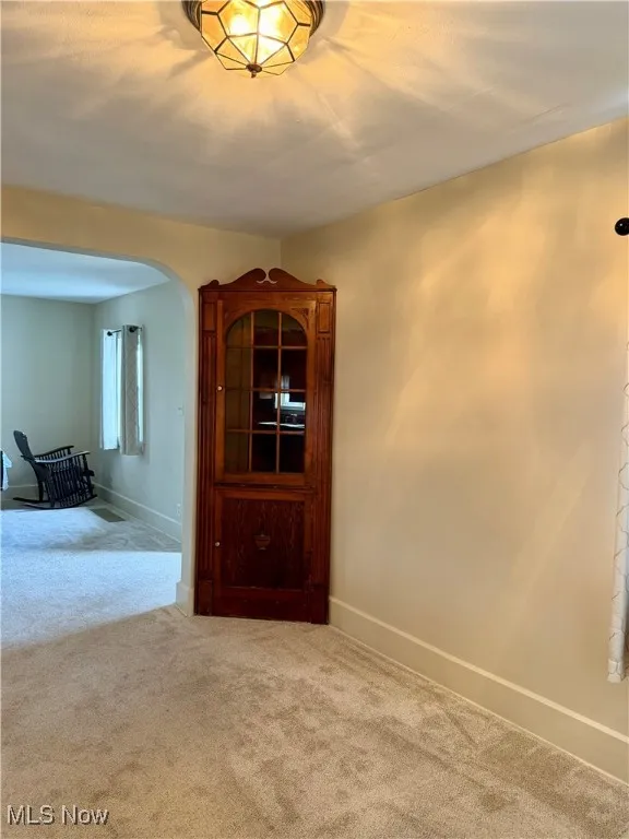 Carpeted dining room with arched walkways and baseboards