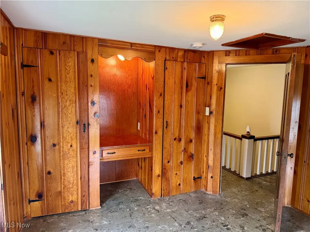 Bedroom featuring wooden walls with built in closets and desk area