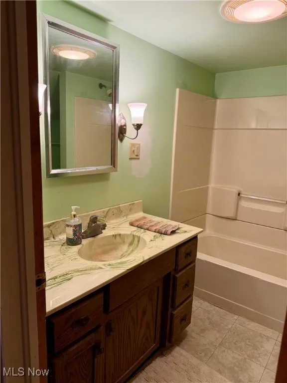 Bathroom featuring vanity, bathtub / shower combination, and light tile patterned floors