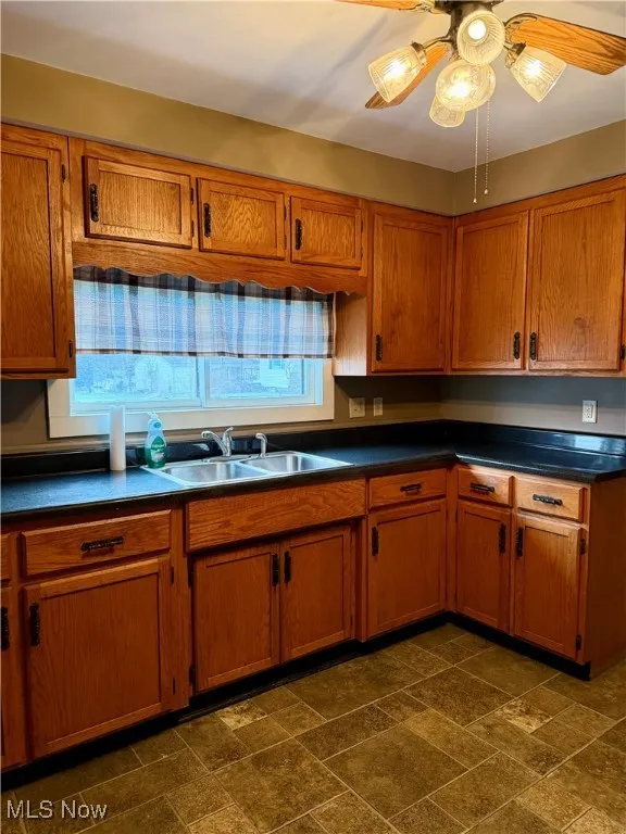 Kitchen featuring dark countertops, brown cabinetry, and stone tile flooring