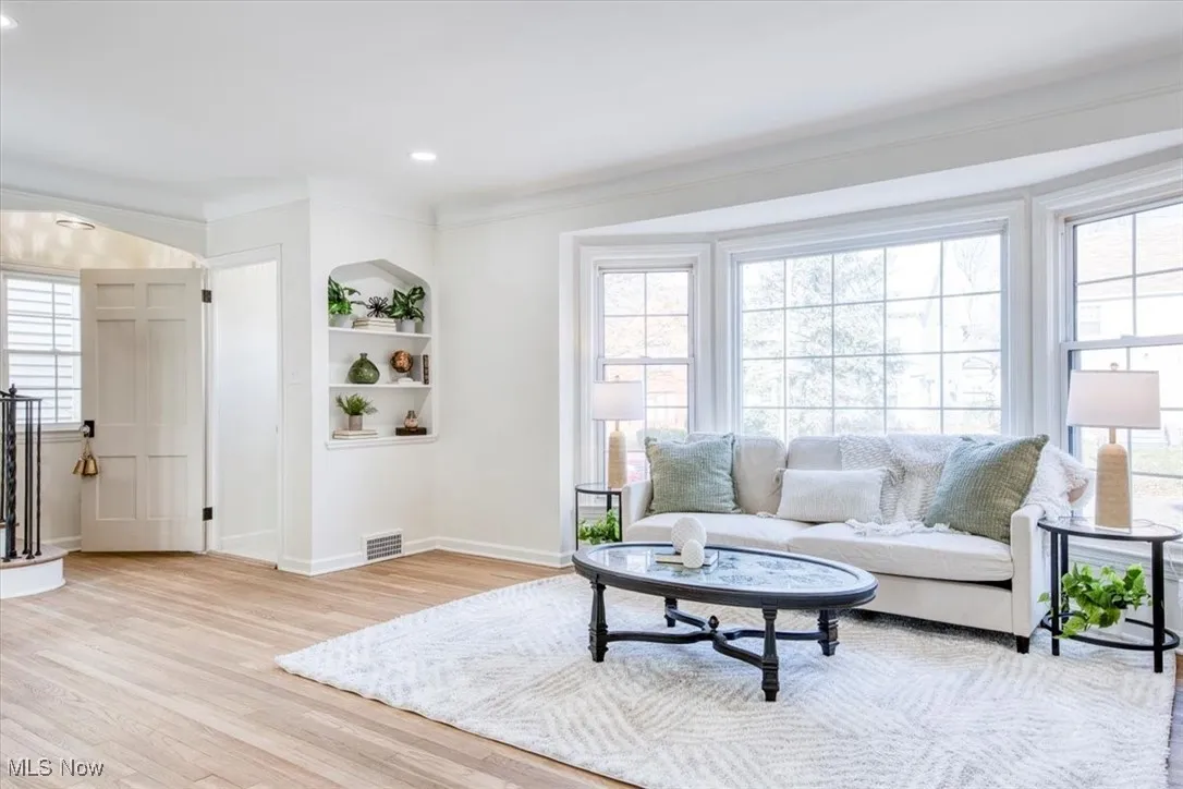 Living area featuring light wood-style flooring, built in features, recessed lighting, and crown molding