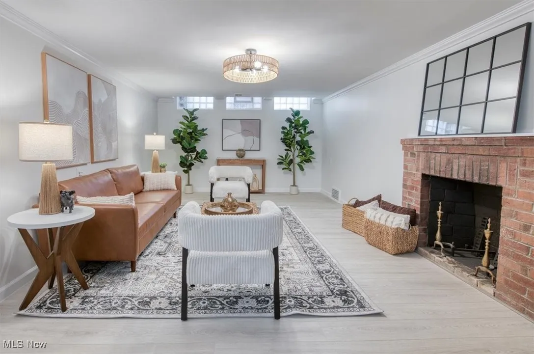 Living area featuring ornamental molding, wood finished floors, and a brick fireplace