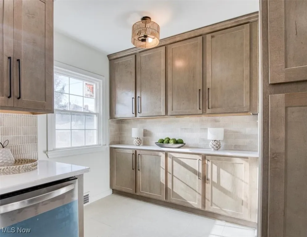 Kitchen with dishwasher, backsplash, and light stone counters