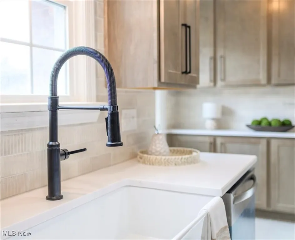 Kitchen view of stainless steel dishwasher, light brown cabinets, and decorative backsplash