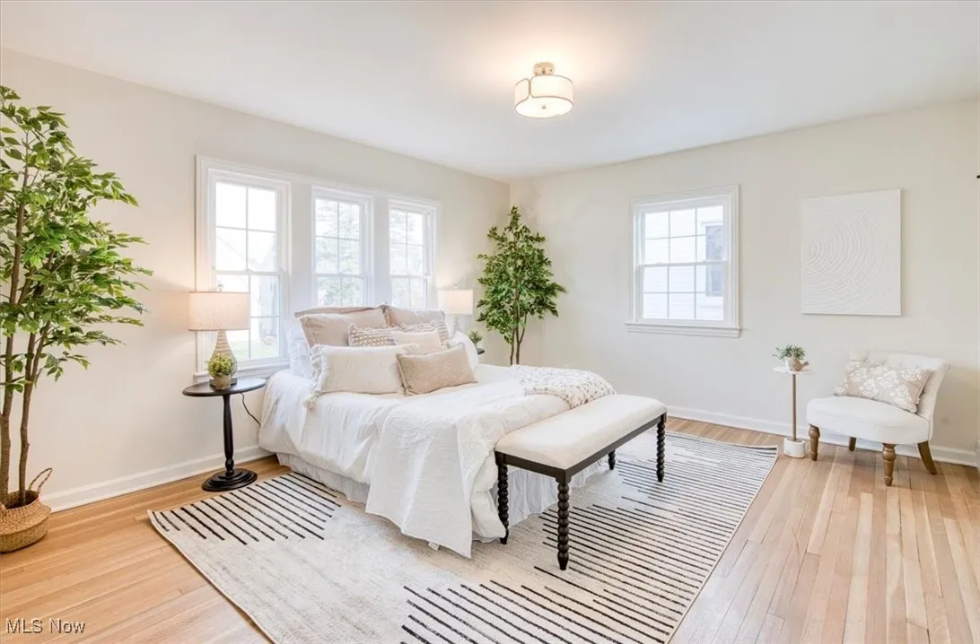 Bedroom with light wood finished floors and multiple windows