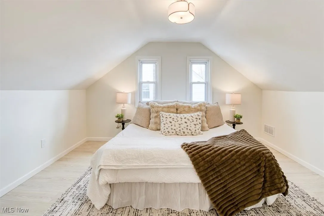 Bedroom featuring light wood finished floors and lofted ceiling