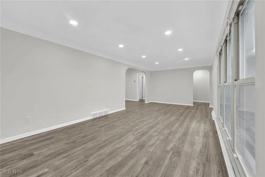 Unfurnished room featuring recessed lighting, arched walkways, and light wood-style floors