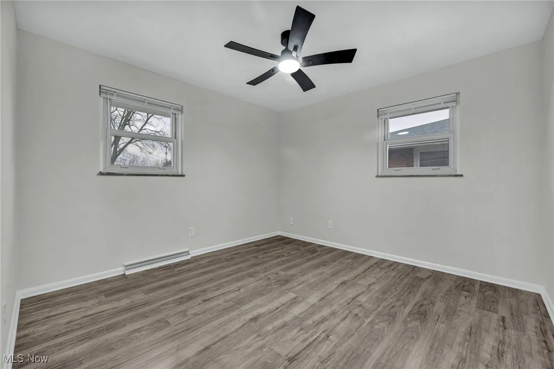 Empty room featuring wood finished floors, baseboard heating, and healthy amount of natural light