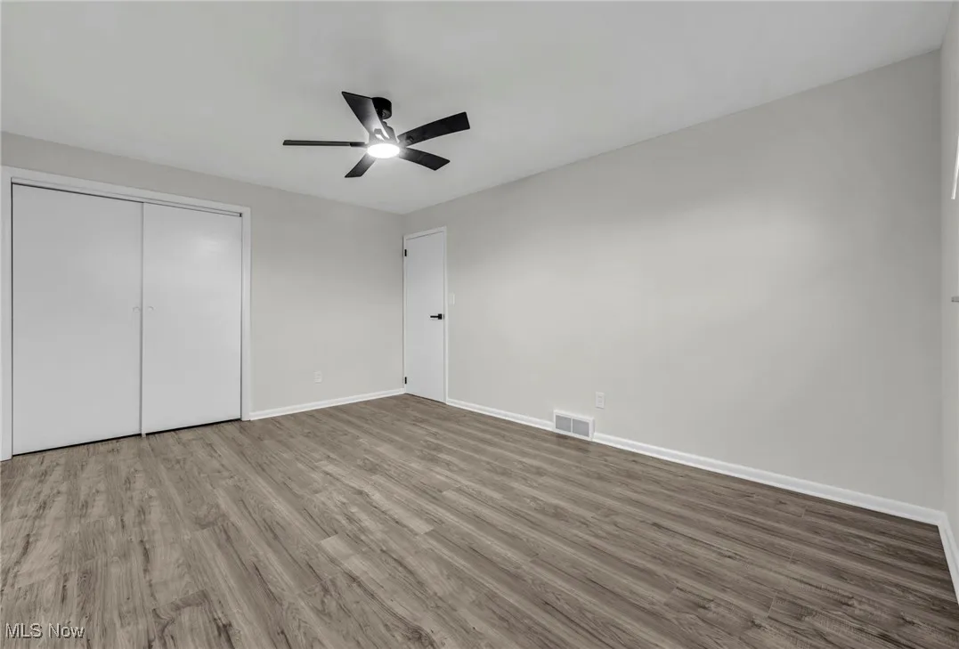 Unfurnished bedroom featuring wood finished floors, a ceiling fan, and a closet