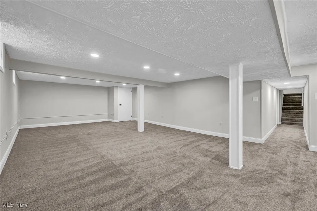 Finished basement with stairs, light carpet, a textured ceiling, and recessed lighting
