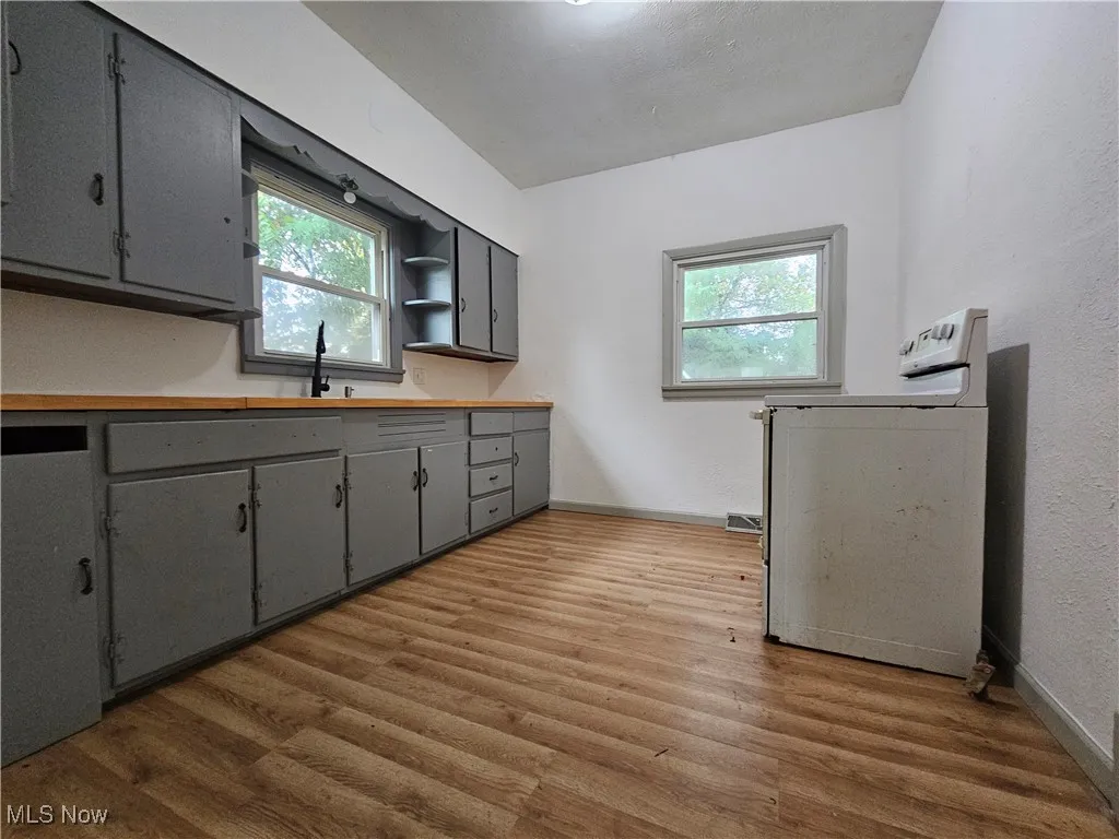 Kitchen with gray cabinetry, light wood finished floors, healthy amount of natural light, and light countertops