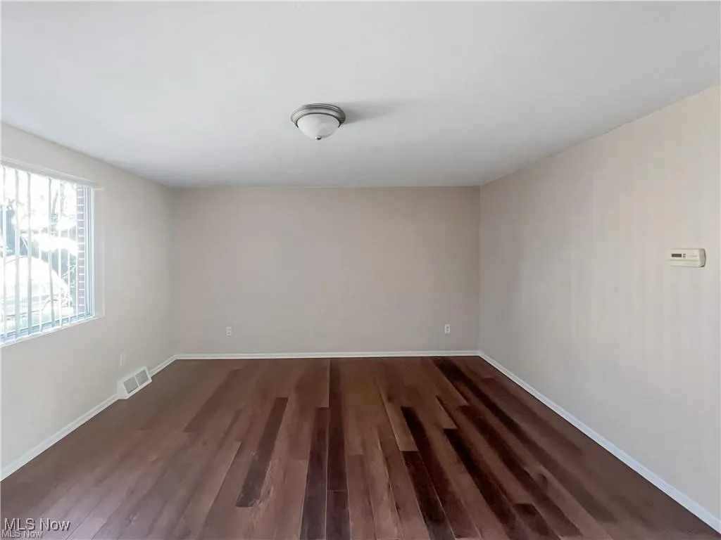Empty room featuring baseboards and dark wood-type flooring