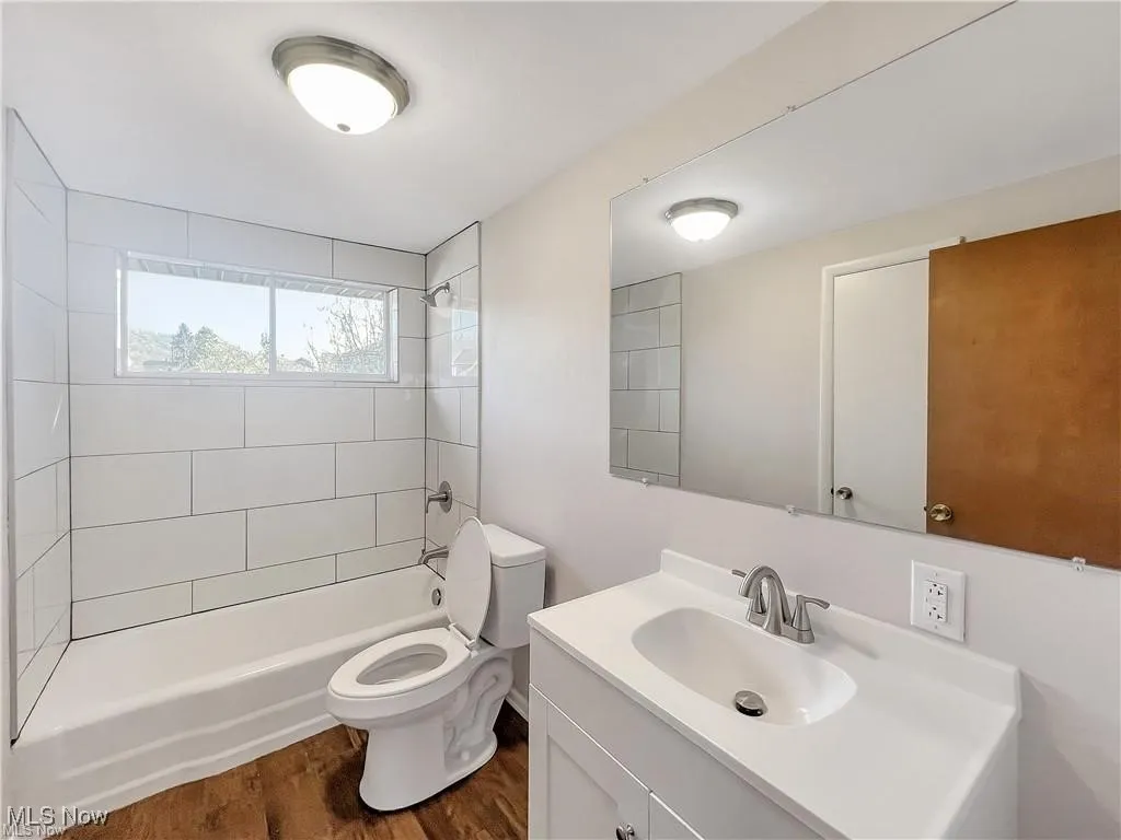 Bathroom featuring vanity, shower / washtub combination, and dark wood-style floors