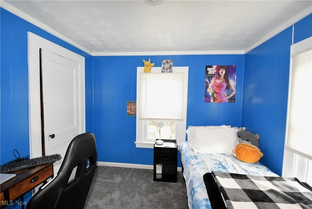 Bedroom featuring dark carpet, ornamental molding, and an office area