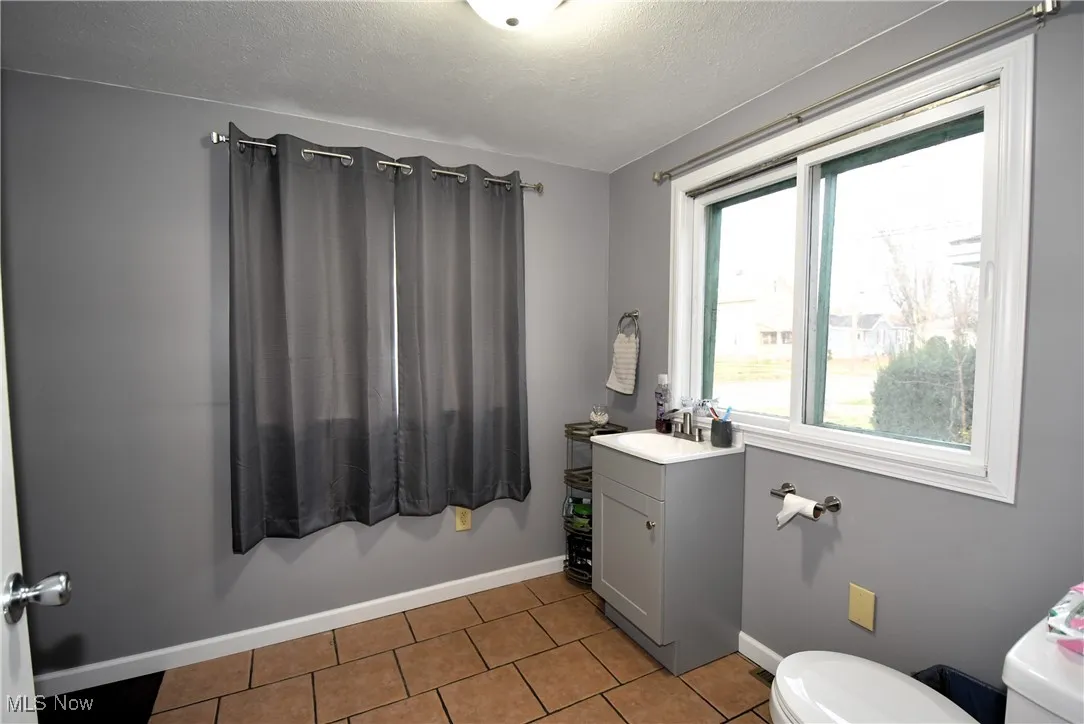 Half bathroom featuring vanity, light tile patterned floors, and a textured ceiling