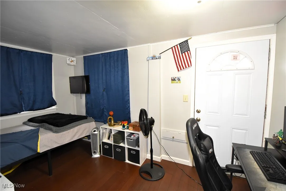 Bedroom with wood finished floors and an office area