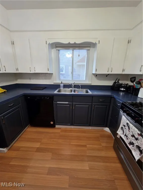 Kitchen with white cabinets, dark countertops, range, and white dishwasher