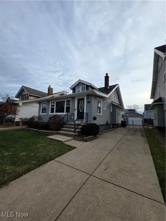 Bungalow-style house with an outdoor structure, a chimney, a front yard, and a garage