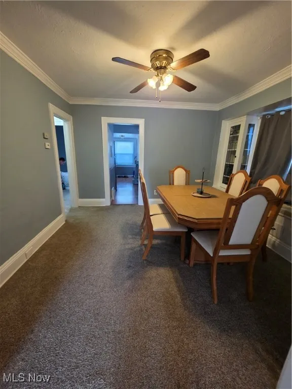Dining space featuring ornamental molding, dark carpet, a textured ceiling, and a ceiling fan