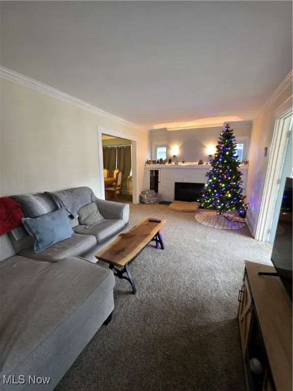 Carpeted living area featuring crown molding and a fireplace