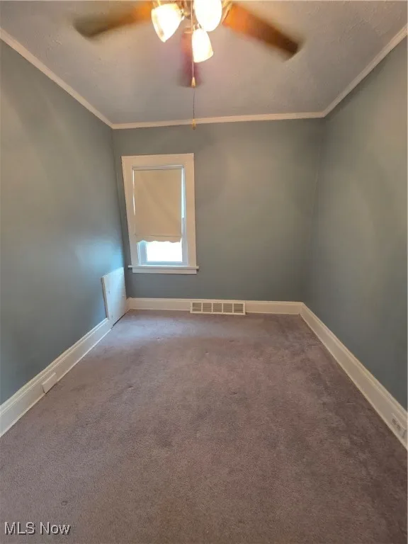 Unfurnished room with a ceiling fan, carpet, and crown molding