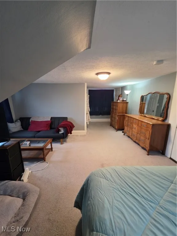 Bedroom with light colored carpet and a textured ceiling