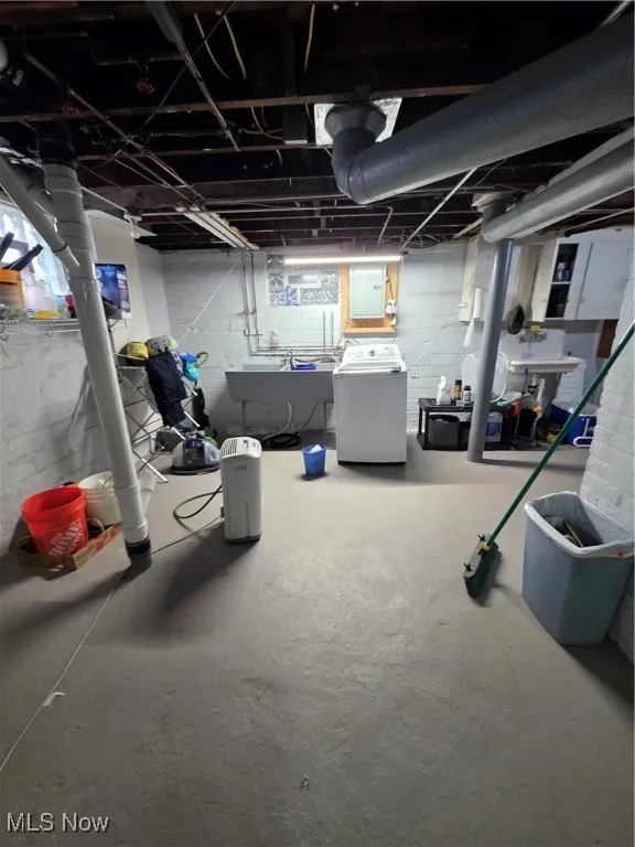 Unfinished basement featuring electric panel and washing machine and clothes dryer