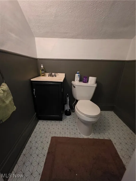 Half bath with vanity, light flooring, and a textured ceiling