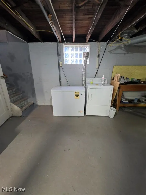 Basement featuring white refrigerator, stairway, and washing machine and dryer