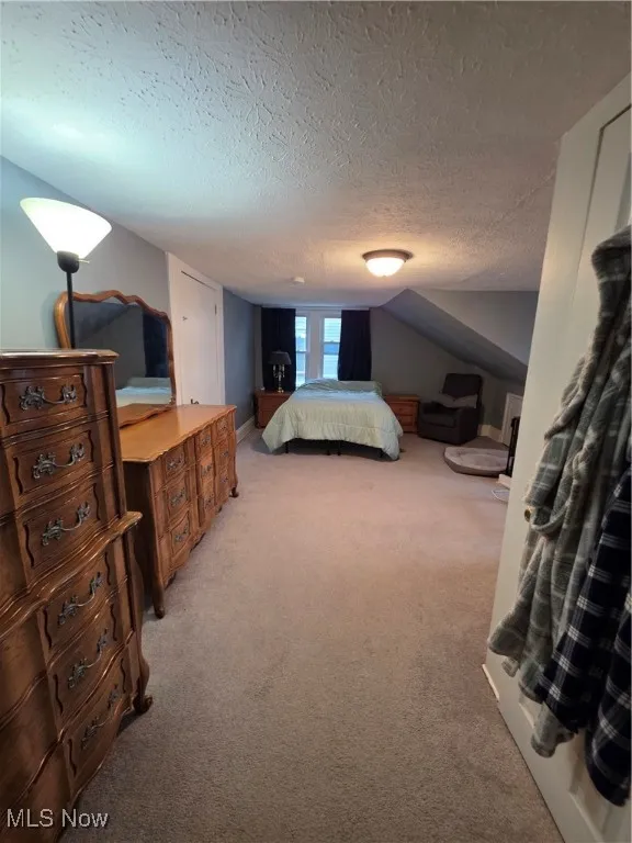 Bedroom featuring light carpet and a textured ceiling