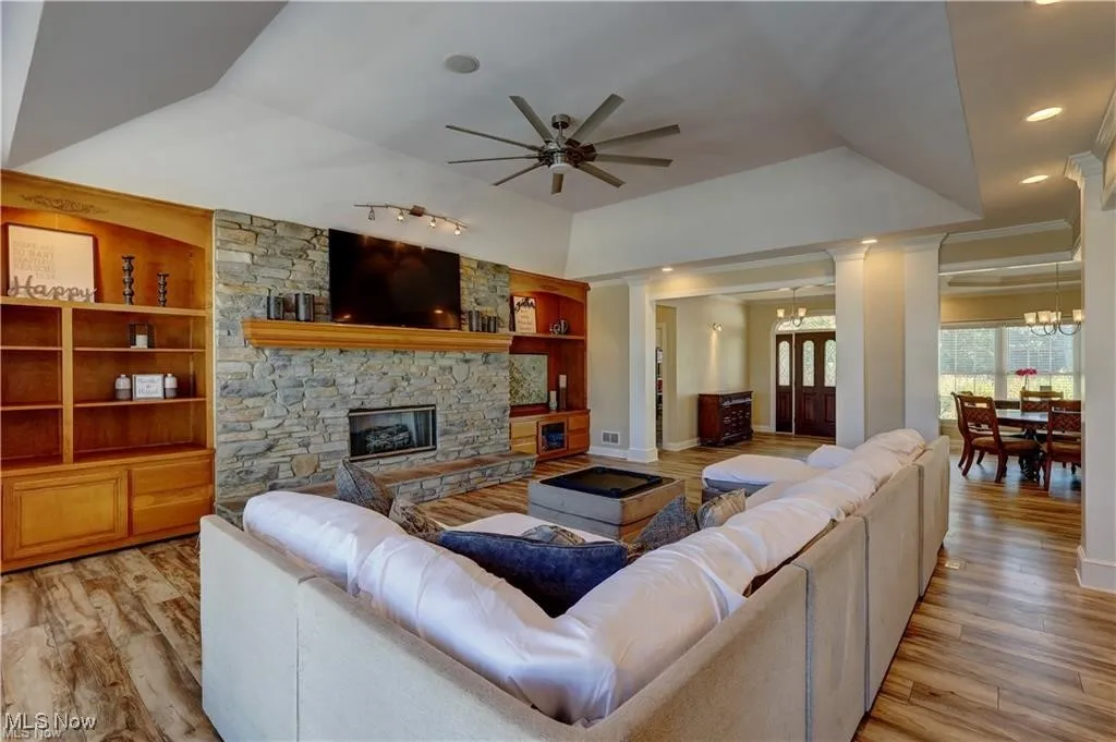 Living room featuring built in shelves, light wood-style flooring, ceiling fan, ornate columns, and recessed lighting
