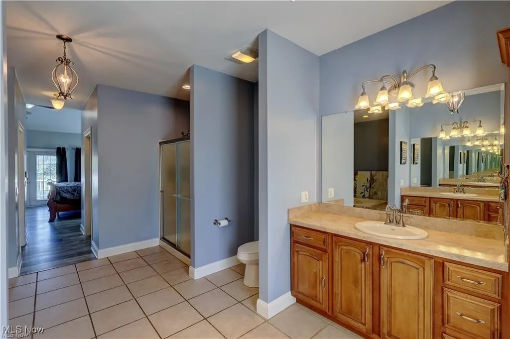 Full bathroom featuring a chandelier, vanity, light tile patterned floors, a stall shower, and ensuite bathroom