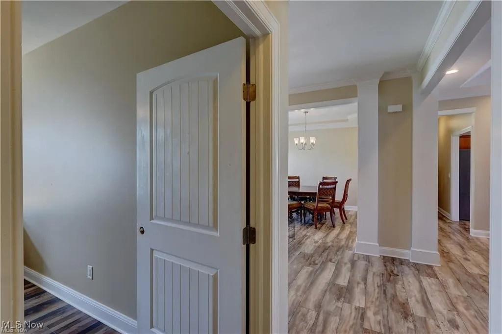 Hallway with light wood-style flooring, a chandelier, crown molding, and recessed lighting